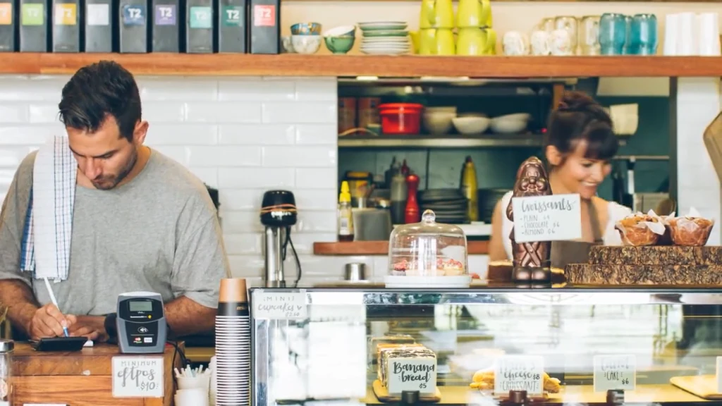 An owner behind the counter of a corner store